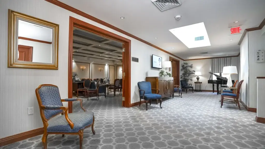 Couloir et aire de réception du salon funéraire Kane Fetterly à Montréal, avec sièges confortables et piano.